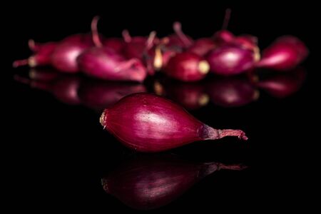 Lot of whole small red onion bulb isolated on black glassの写真素材