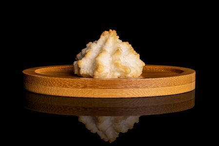 One whole homemade golden coconut biscuit on bamboo coaster isolated on black glassの写真素材