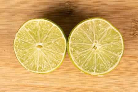 Group of two halves of sour green lime flatlay on light wood