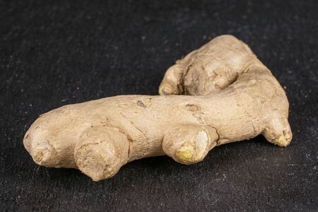 One whole fresh brown ginger on grey stone