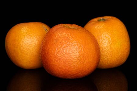 Group of three whole bright fresh orange mandarin isolated on black glassの写真素材