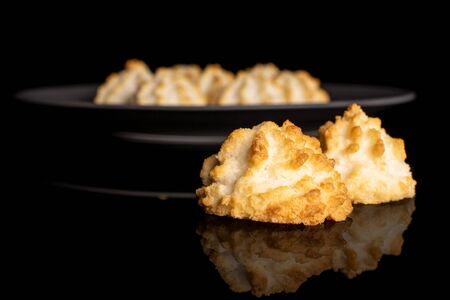 Lot of whole homemade golden coconut biscuit on gray ceramic plate isolated on black glassの写真素材