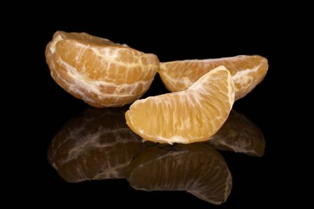 Group of one half two pieces of fresh orange mandarin isolated on black glassの写真素材