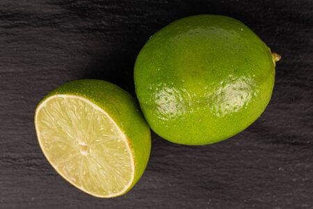 Group of one whole one half of sour green lime flatlay on grey stoneの写真素材