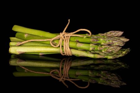 Lot of whole healthy green asparagus with straw rope isolated on black glassの写真素材
