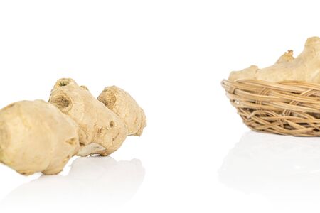 Lot of whole fresh brown ginger in round rattan bowl isolated on white background