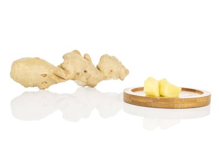 Group of one whole three pieces of fresh brown ginger on round bamboo coaster isolated on white...