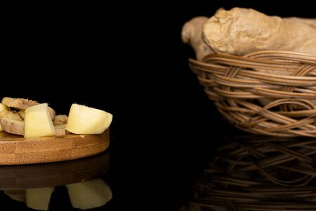 Group of lot of whole three slices two pieces of fresh brown ginger in round rattan bowl on round...