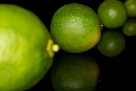 Group of four whole sour green lime isolated on black glassの写真素材