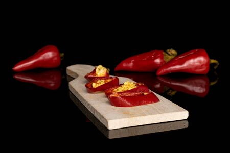 Group of three whole four slices of pickled red pepper on wooden cutting board isolated on black glassの写真素材