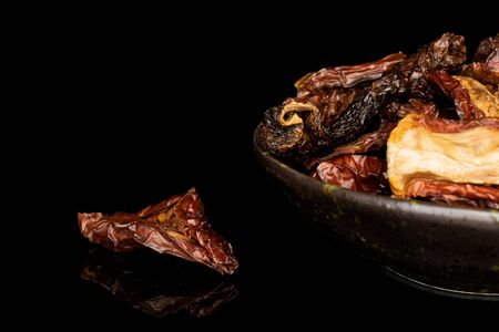 Lot of whole dried red tomato piece in glazed bowl isolated on black glassの写真素材