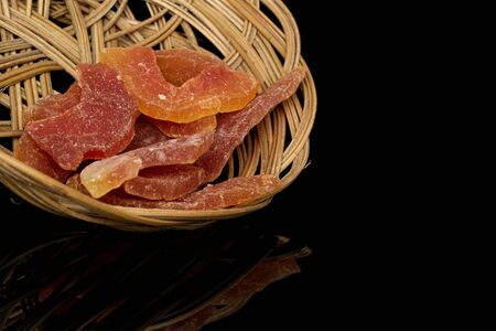 Lot of whole dried orange papaya piece in round rattan bowl isolated on black glassの写真素材