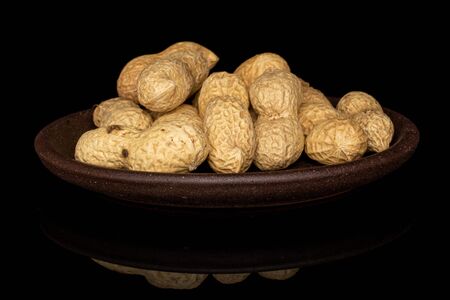 Lot of whole tasty beige peanut with brown ceramic coaster isolated on black glassの写真素材