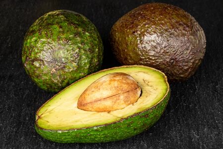 Group of two whole one half of fresh green avocado on grey stoneの写真素材