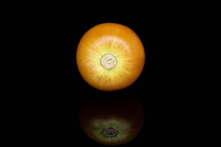 One whole fresh orange physalis isolated on black glassの写真素材
