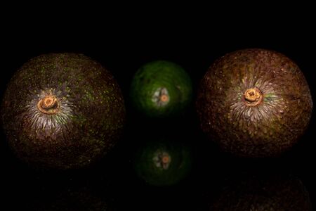 Group of three whole fresh green avocado isolated on black glassの写真素材