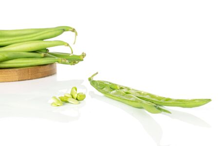 Group of lot of whole two halves lot of pieces of snap green bean on round bamboo coaster isolated on white backgroundの写真素材