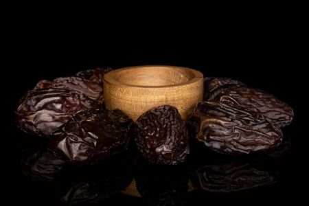 Lot of whole dried brown date fruit around bowl isolated on black glassの写真素材