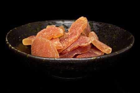 Lot of whole dried orange papaya piece in glazed bowl isolated on black glassの写真素材