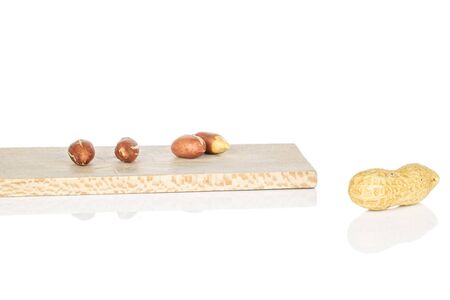 Group of one whole four pieces of tasty beige peanut on wooden cutting board isolated on white...