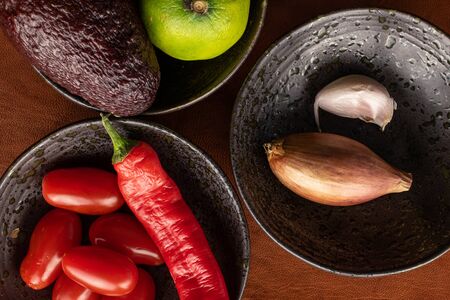 Lot of whole ingredient guacamole in glazed bowl flatlay on cognac leatherの写真素材