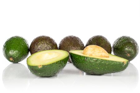 Group of five whole two halves of fresh green avocado isolated on white background