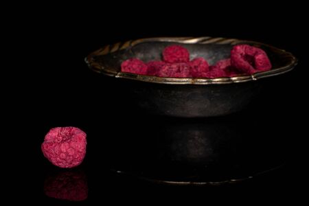 Lot of whole dried raspberry in copper bowl isolated on black glassの写真素材