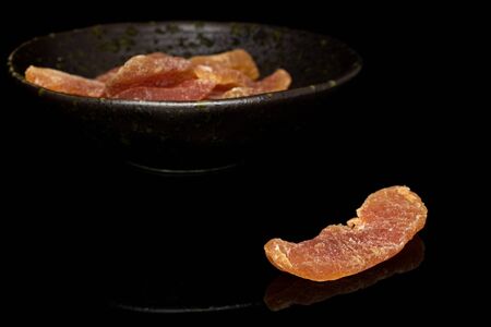Lot of whole dried orange papaya piece in glazed bowl isolated on black glassの写真素材