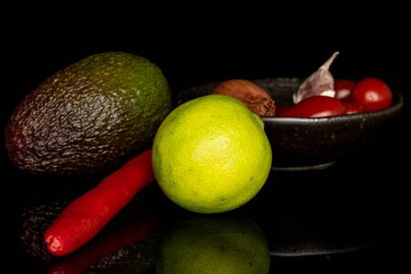 Lot of whole ingredient guacamole in glazed bowl isolated on black glass