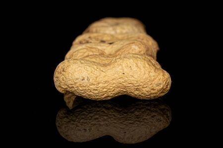 Lot of whole tasty beige peanut in row isolated on black glass