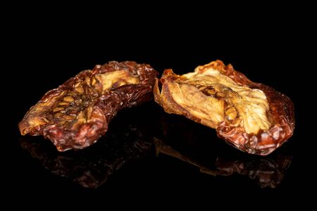 Group of two whole dried red tomato piece isolated on black glassの写真素材