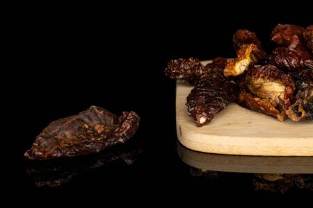 Lot of whole dried red tomato piece on bamboo cutting board isolated on black glassの写真素材