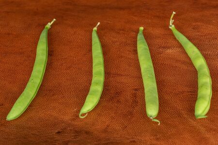 Group of four whole snap green bean on cognac leather