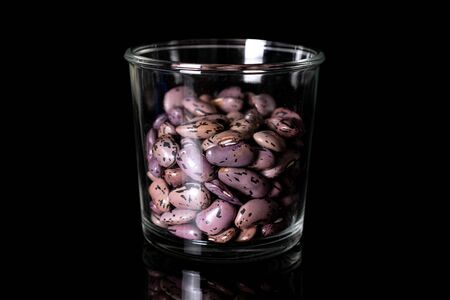 Lot of whole fresh speckled bean pinto in glass beaker isolated on black glassの写真素材