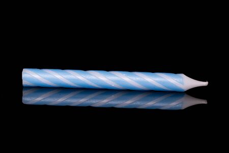One whole blue birthday cake candle isolated on black glassの写真素材