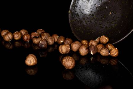 Lot of whole peeled tasty brown hazelnut in glazed bowl isolated on black glassの写真素材