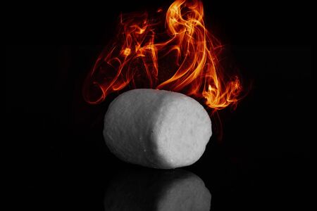 One sweet fluffy marshmallow with fire isolated on black glassの写真素材
