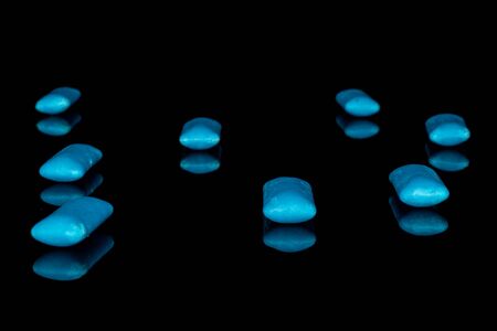 Group of eight whole blue chewing gum isolated on black glass