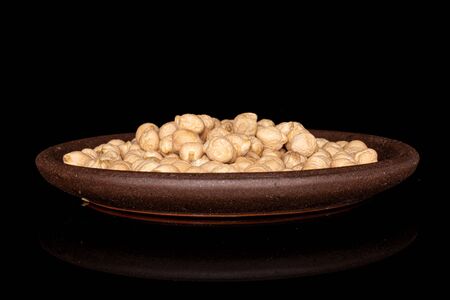 Lot of whole fresh tan chickpea with brown ceramic coaster isolated on black glassの写真素材