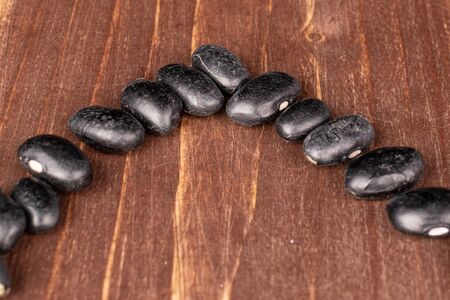 Lot of whole small black bean on brown wood
