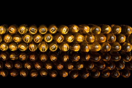 Lot of whole golden fish oil isolated on black glass