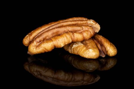 Group of two whole tasty brown pecan half isolated on black glass