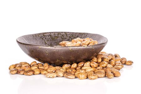 Lot of whole uncooked mottled brown bean pinto in glazed bowl isolated on white background