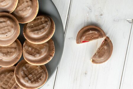 Group of lot of whole two halves of chocolate biscuit on gray ceramic plate flatlay on white wood
