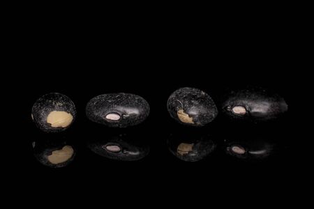 Group of four whole black bean isolated on black glass