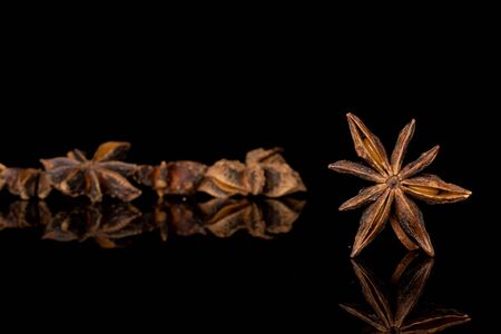 Lot of whole arranged aromatic brown badian isolated on black glassの写真素材
