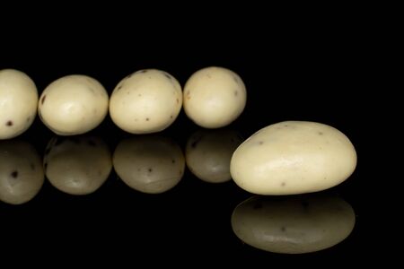 Group of five whole coated white almond nut stracciatella isolated on black glass