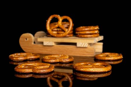 Lot of whole salty brown pretzel with wooden sledge isolated on black glassの写真素材