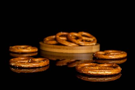 Lot of whole salty brown pretzel on bamboo coaster isolated on black glassの写真素材