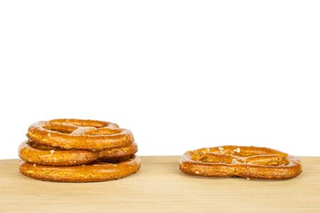 Group of four whole salty brown pretzel on bamboo cutting board isolated on white background